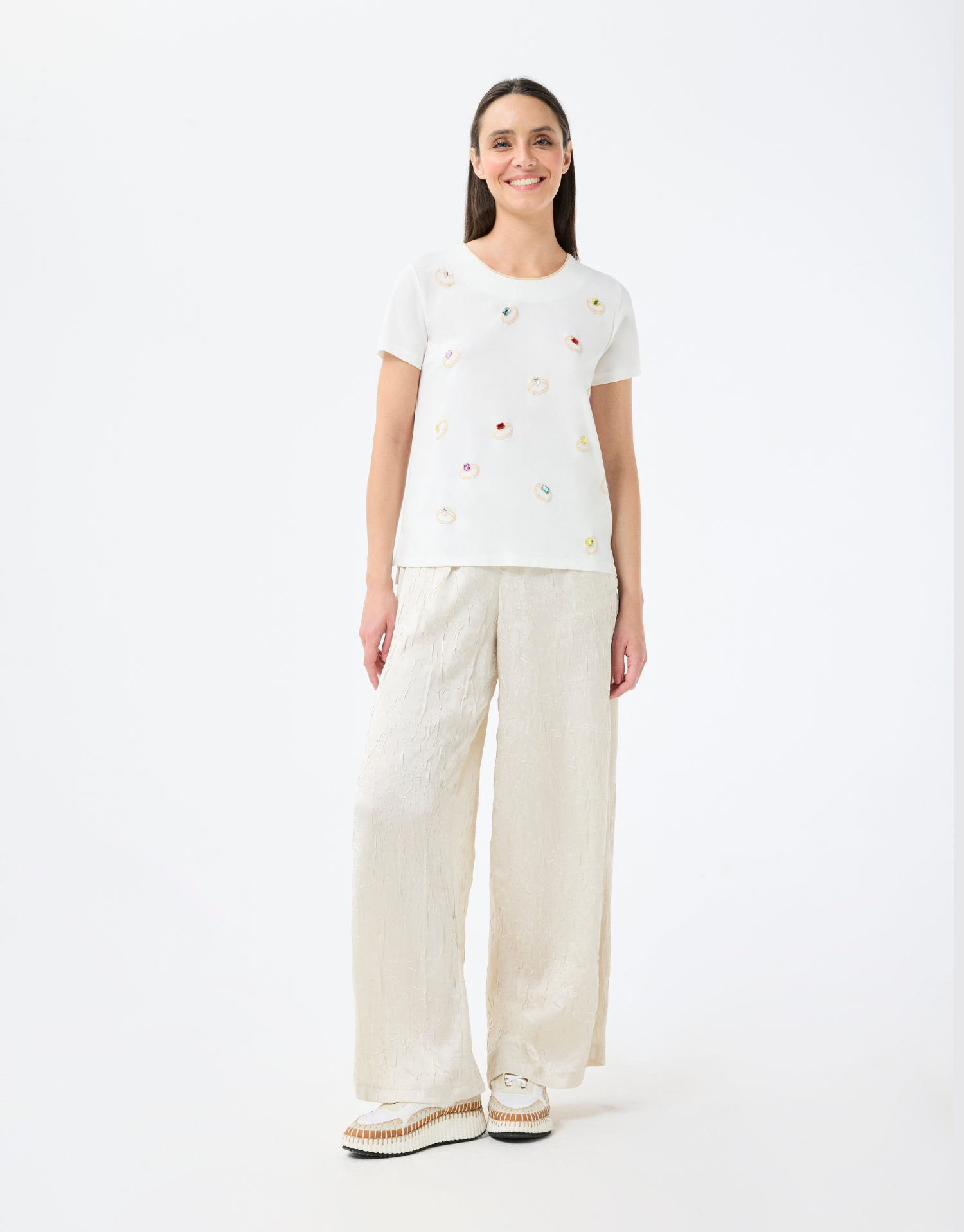 t-shirt col rond écru en coton, manches courtes avec couture dorée autour du col, imprimé bagues colorées, style moderne et audacieux