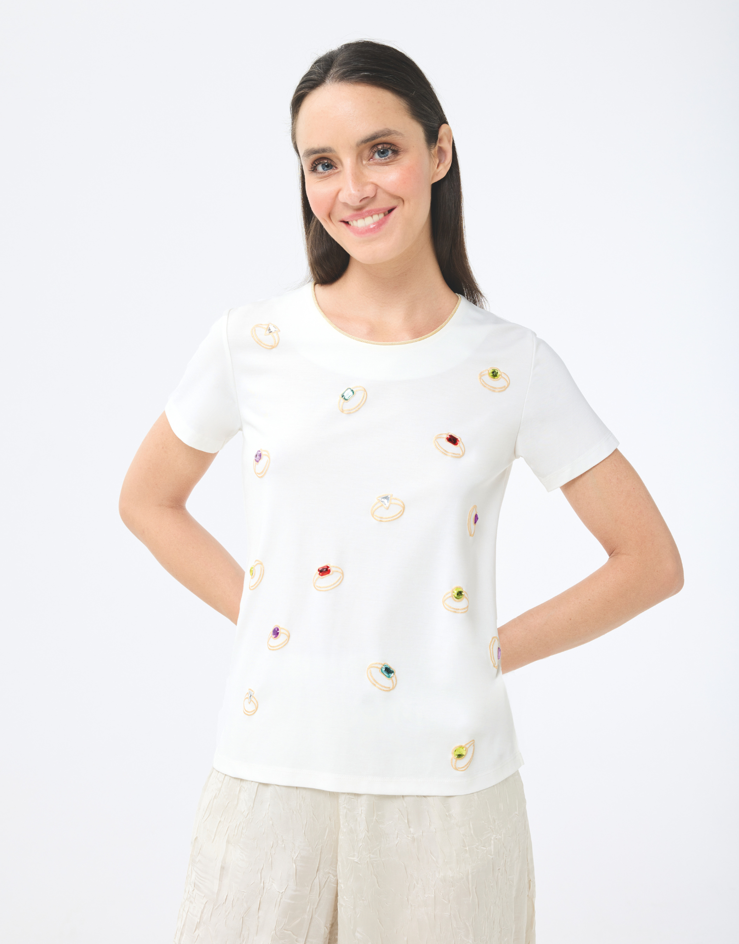 t-shirt col rond écru en coton, manches courtes avec couture dorée autour du col, imprimé bagues colorées, style moderne et audacieux