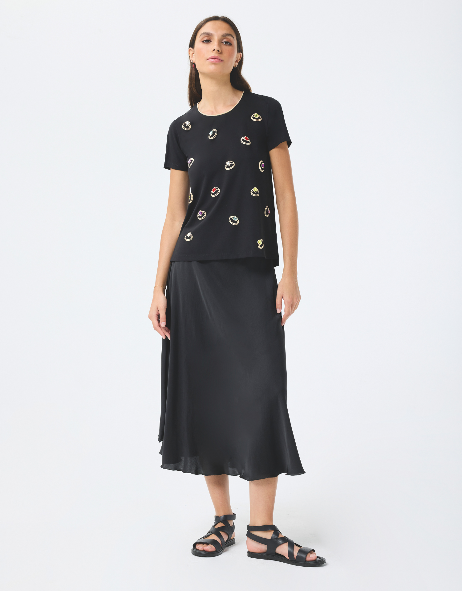 t-shirt col rond noir en coton, manches courtes avec couture dorée autour du col, imprimé bagues colorées, style moderne et audacieux
